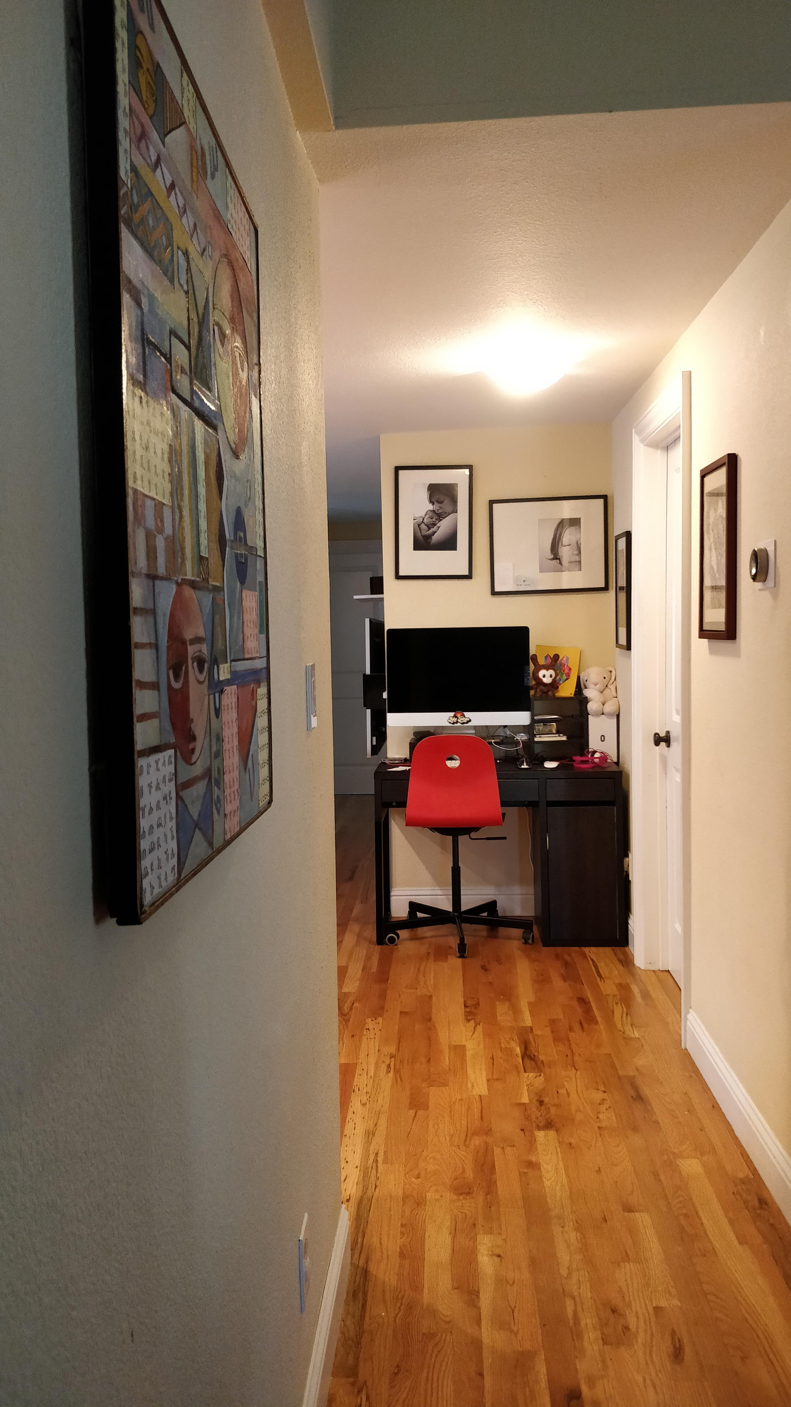 Corner desk down the hall with a geometric abstraction art on the left side wall
