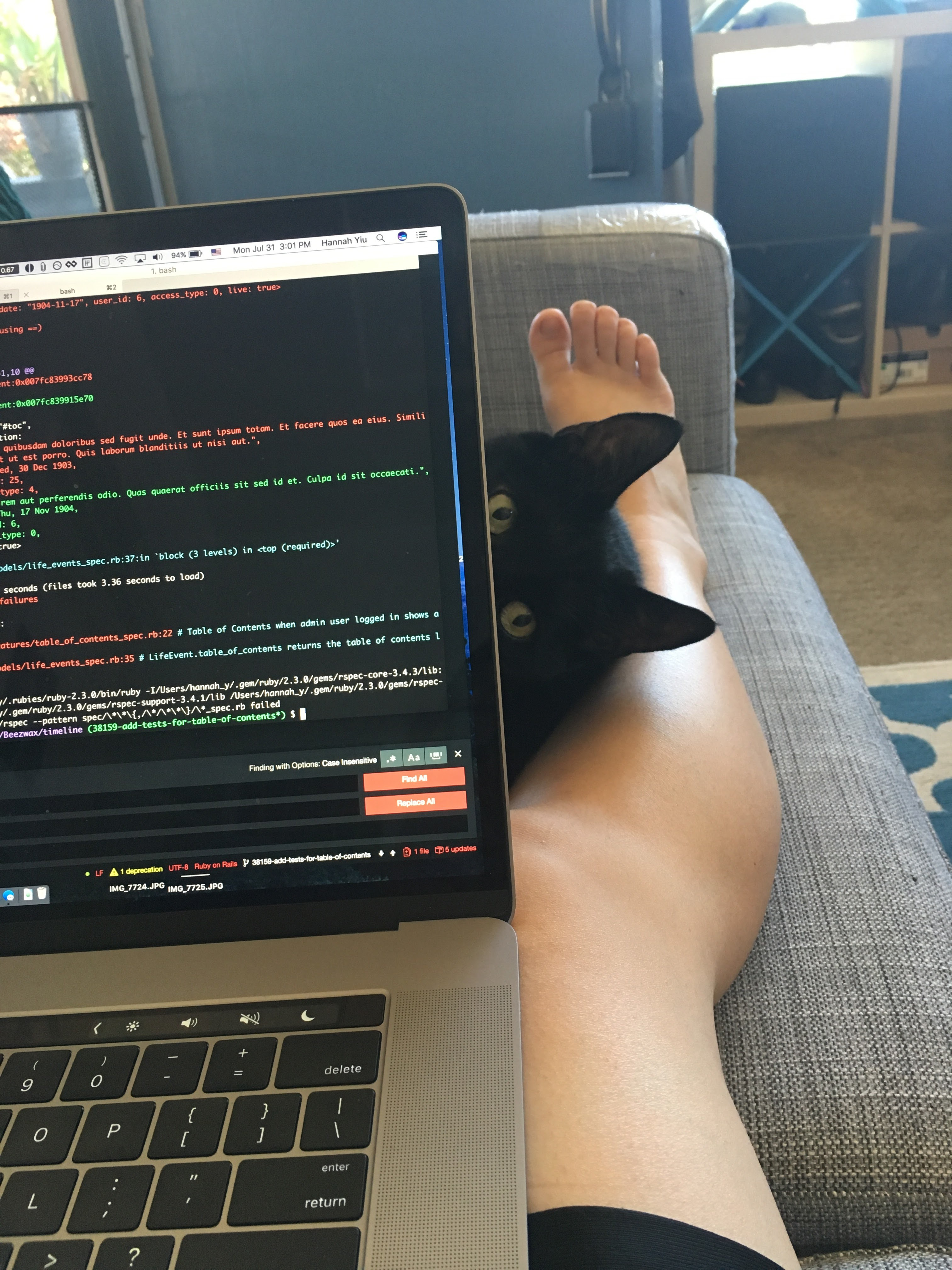 black cat peeking behind laptop